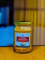 A single jar of Naveen Turmeric Ginger Shots placed on a wooden table with a softly blurred golden-yellow background.