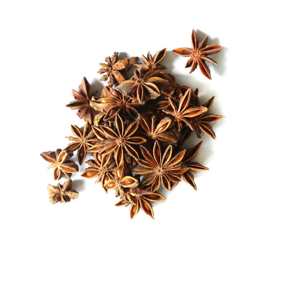 Pile of whole star anise pods from Naveen Herbs on a white background
