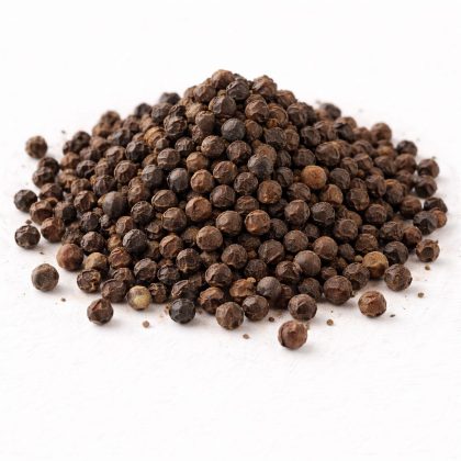 Pile of black pepper seeds on white textured background