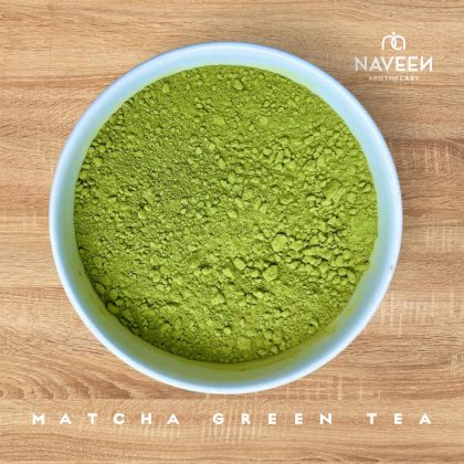A bowl of bright green matcha green tea powder on a wooden surface with the Naveen Apothecary logo.