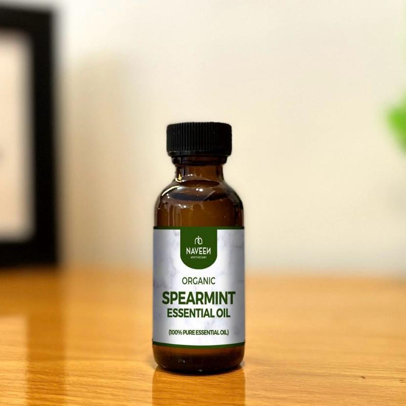 Naveen Herbs Co organic spearmint essential oil bottle on wooden table showing 100 percent pure essential oil for aromatherapy and herbal wellness