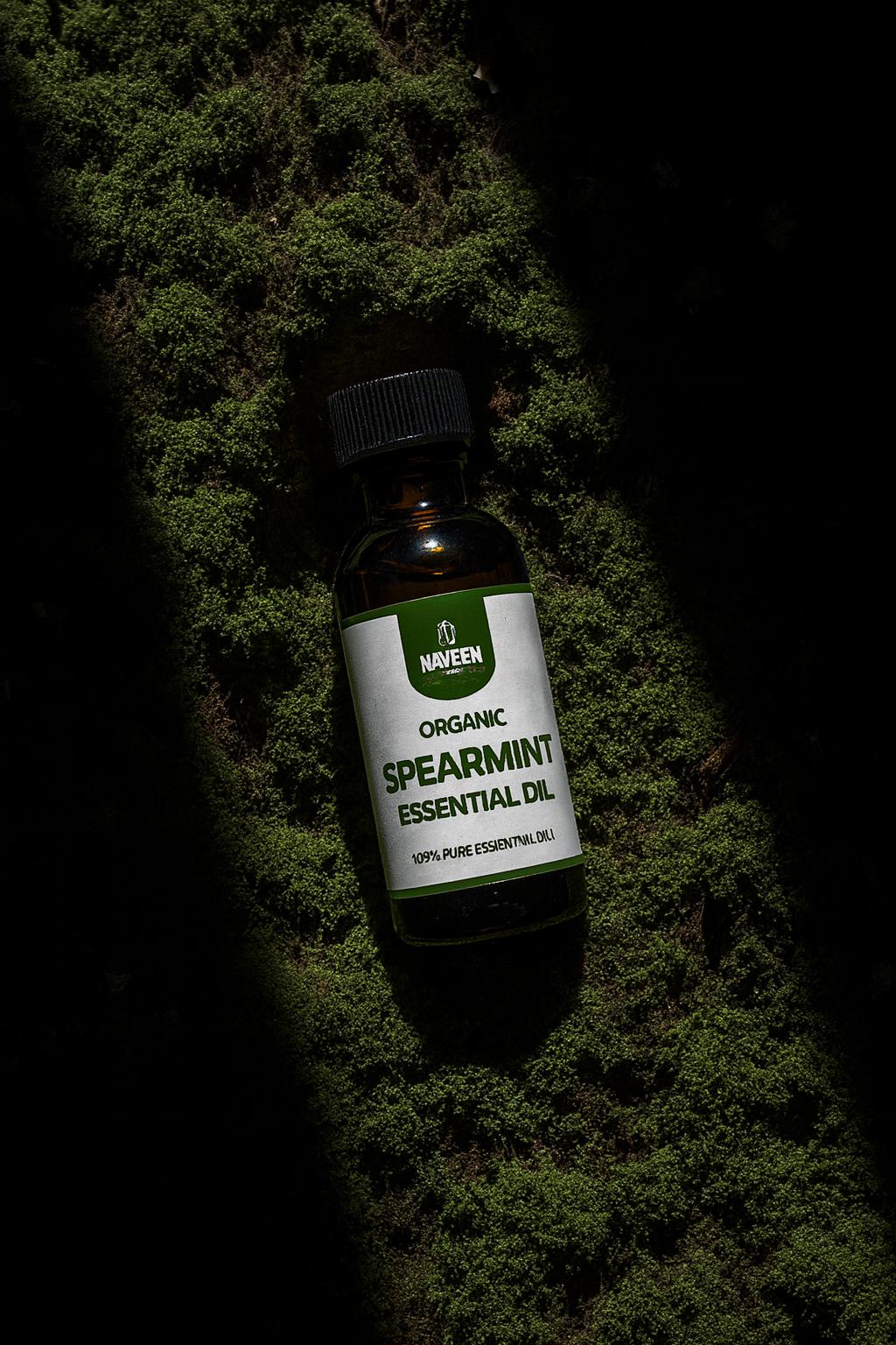 Bottle of organic spearmint essential oil by Naveen Herbs Co placed on natural moss surface highlighting pure herbal essential oil for aromatherapy and wellness